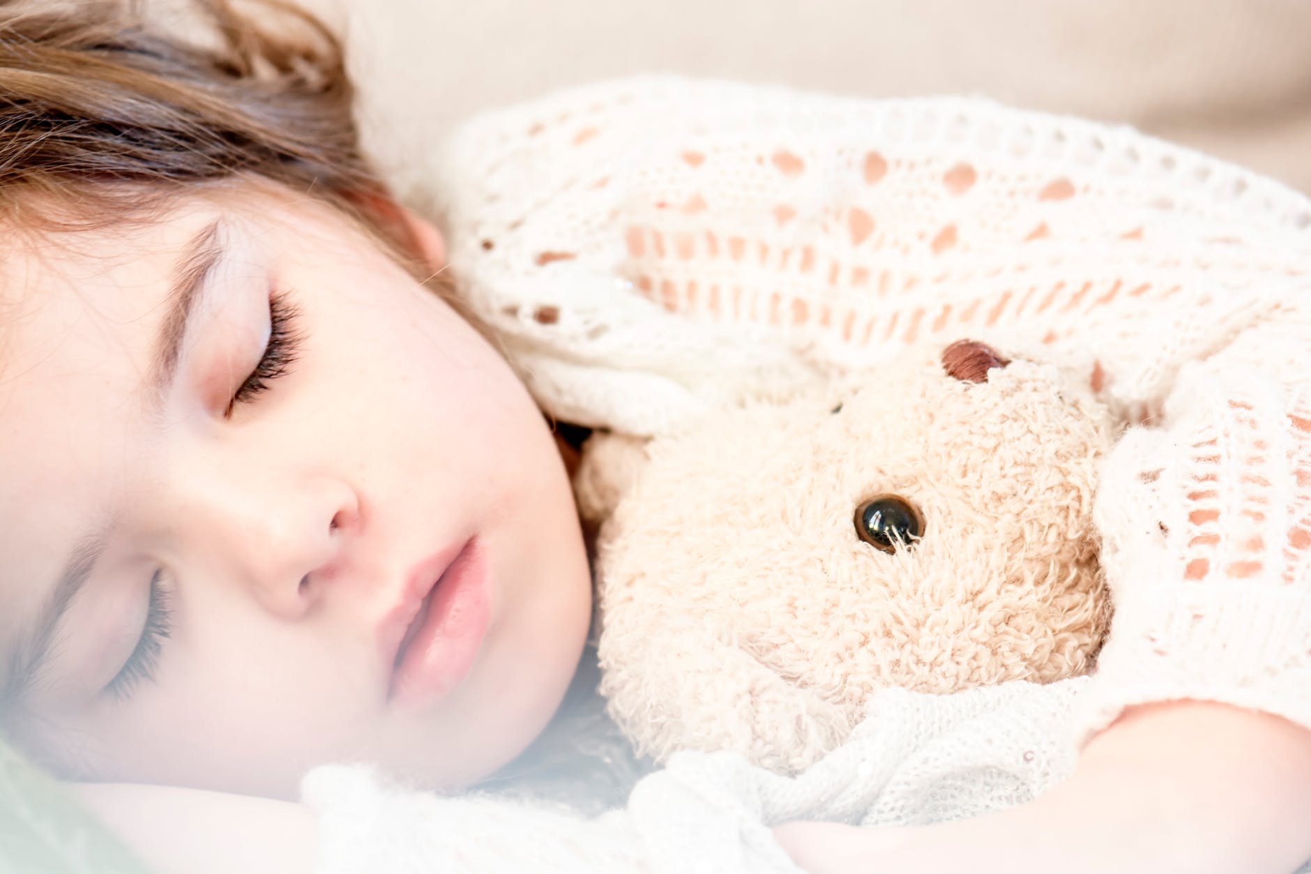 girl sleeping with her brown plush toy
